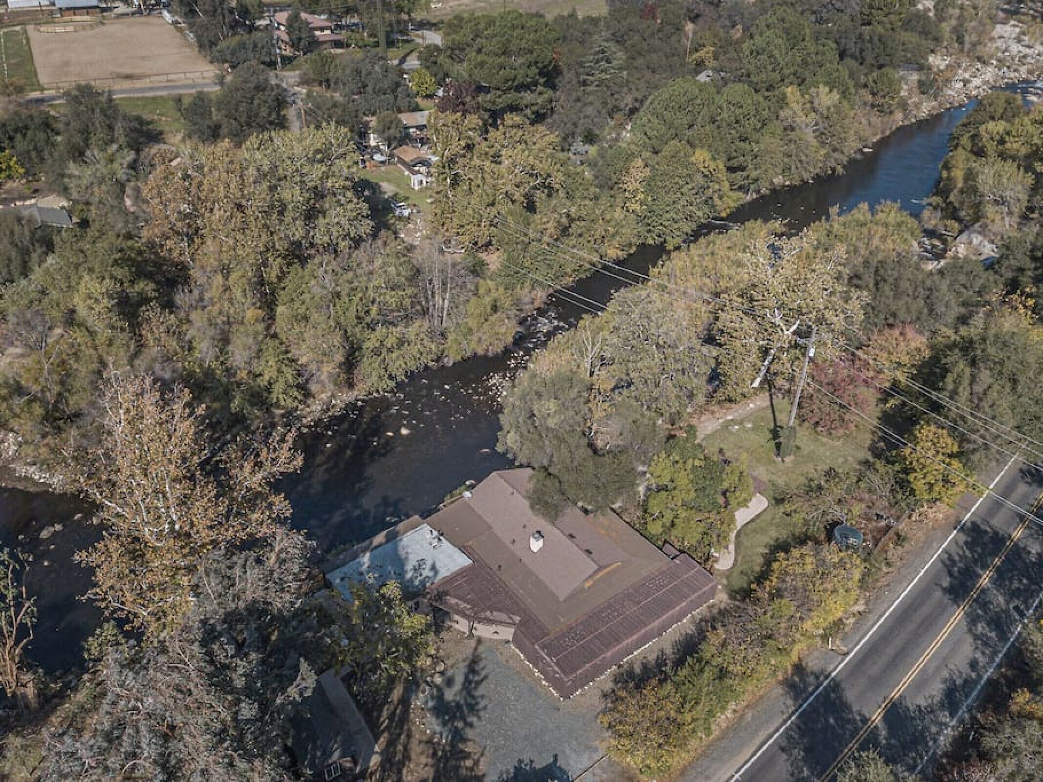 An aerial view of a residential area with a river, houses, and a road.