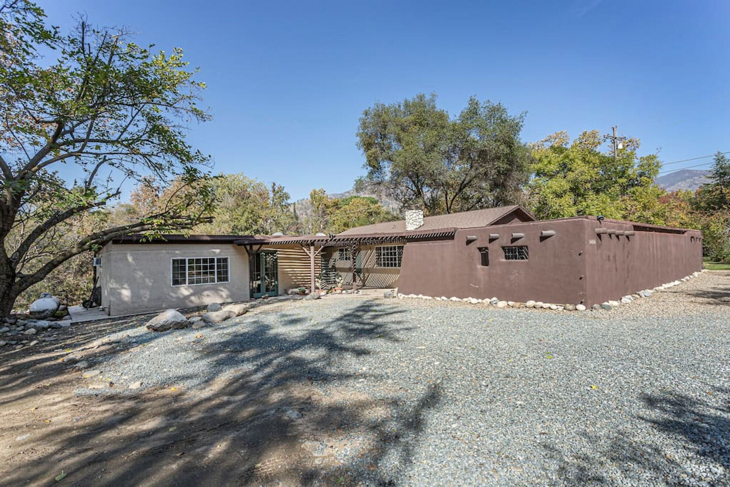 A two-story house with a gravel driveway and a small patio area.