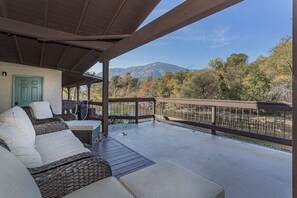 Ein überdachter Außenbereich mit Korbmöbeln und Blick auf eine gebirgige Landschaft.