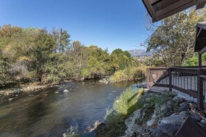 Ein Fluss mit einer Holzbrücke und einem Gebäude mit einem Zaun.