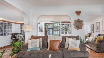Ein gemütliches Wohnzimmer mit einem grauen Sofa, einer Stehlampe und einem Spiegel an der Wand.