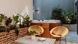 A cozy outdoor seating area with two wicker chairs, a wooden bench, and a small table with books and a potted plant. - - 201 Provenza ⚡ Astonishing 3BR - A/C ⚡ Private Jacuzzi (Medellín)