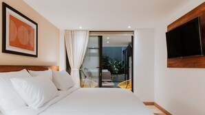 A hotel room with a large bed, a flat-screen TV, a framed picture, and a sliding glass door leading to an outdoor area with chairs. - - 201 Provenza ⚡ Astonishing 3BR - A/C ⚡ Private Jacuzzi (Medellín)
