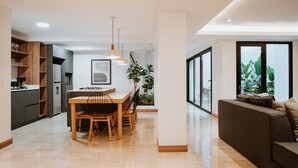 A modern kitchen with a dining area, a sofa, and a large window with a view of greenery. - - 201 Provenza ⚡ Astonishing 3BR - A/C ⚡ Private Jacuzzi (Medellín)
