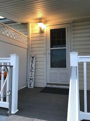 Enter through the welcoming entrance, flanked by white railings and a cozy porch.