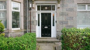 A stone building with a black door, a small porch, and a window to the left.