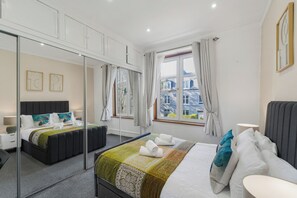 Ein modernes Hotelzimmer mit einem großen Bett, einem Spiegel, einem Nachttisch, einem Fenster mit Vorhängen und Blick auf die Stadt.