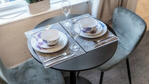 A table set with two bowls, a glass, and cutlery on a round table with a chair.