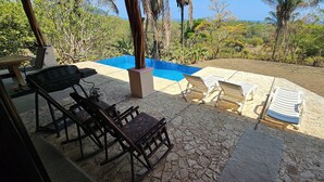 A patio area with a pool, outdoor seating, and a view of the surrounding landscape. - Great House (Guanacaste Province)