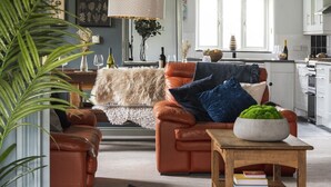 Een moderne woonkamer met leren banken, een houten salontafel en een groot raam.