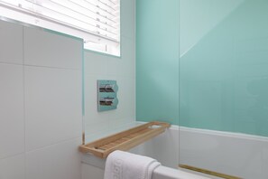 A bathroom with a white toilet, a wooden shelf, and a glass shower enclosure. - Shippen (Kingsbridge)