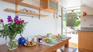 Una mesa de desayuno con cuencos verdes, platos y un jarrón de flores.