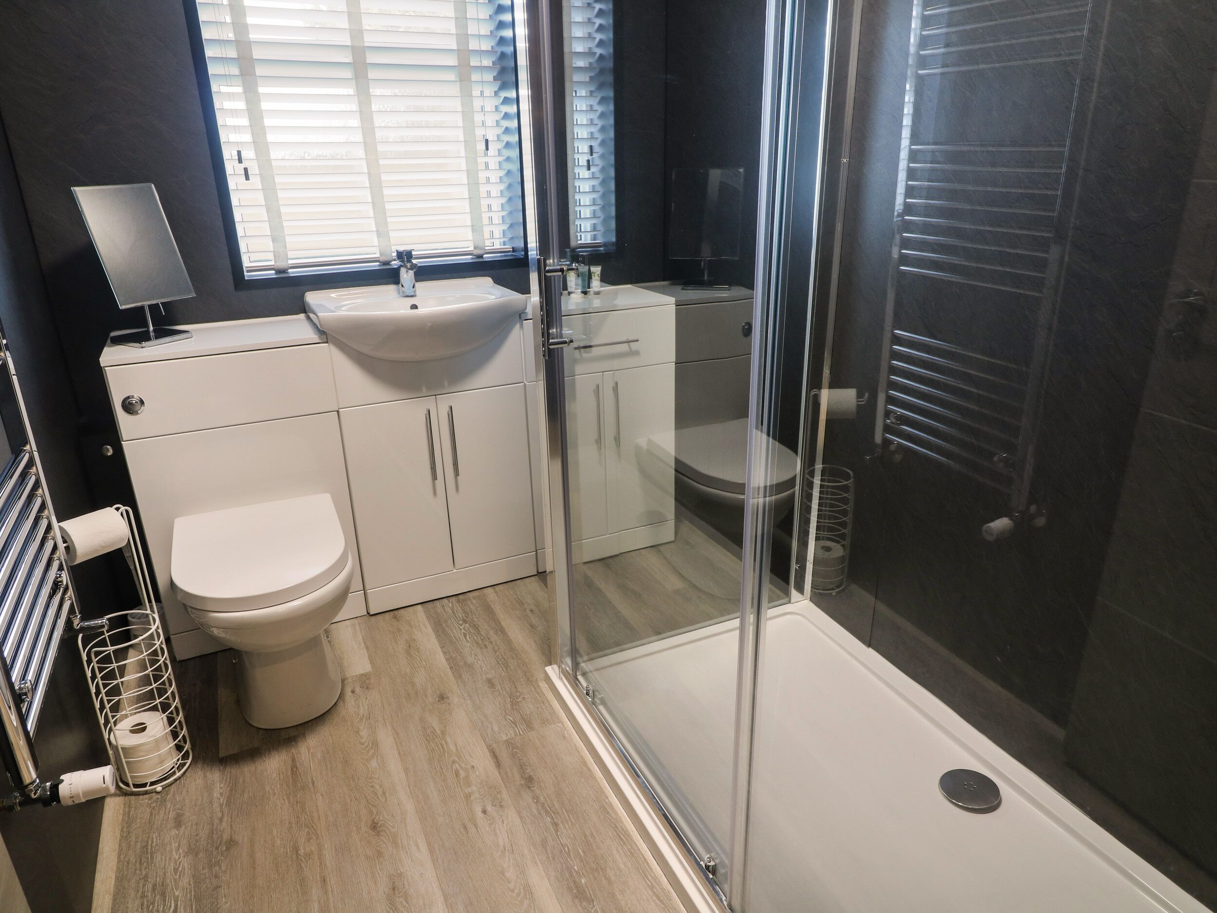 Un baño moderno con cabina de ducha de vidrio, un lavabo blanco y un inodoro.