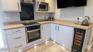 A modern kitchen with white cabinetry, a built-in oven, a microwave, a toaster, and a kettle. - White Stones (Ulverston)