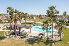 Ett bostadsområde med en swimmingpool omgiven av palmer och en lusthus.
