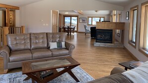 A spacious living room with a leather sofa, a glass coffee table, and a fireplace.