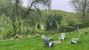 A grassy outdoor area with Adirondack chairs and a fire pit.