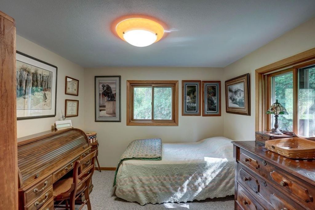 A bedroom with a bed, dresser, desk, and framed pictures on the wall.