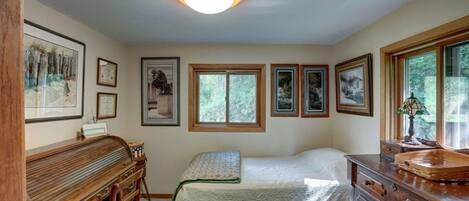 A bedroom with a bed, dresser, desk, and framed pictures on the wall.