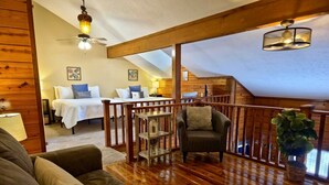 A cozy loft bedroom with a wooden ceiling, a bed with white bedding, a chair, and a plant. - Cozy Cabin~Sleeps 6~Great Location~Dog-Friendly (Branson)