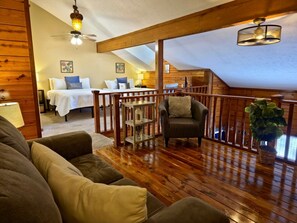 A cozy loft bedroom with a wooden ceiling, a bed with white bedding, a chair, and a plant.