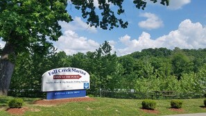 A sign for Fall Creek Marina, indicating it is open to the public and offers boat rentals, fishing supplies, and snacks.