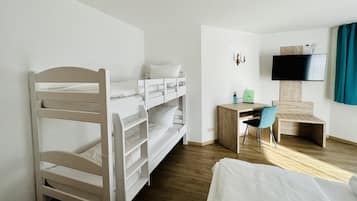 Camera con letto a castello, una scrivania, una sedia, una televisione e una finestra con tende.