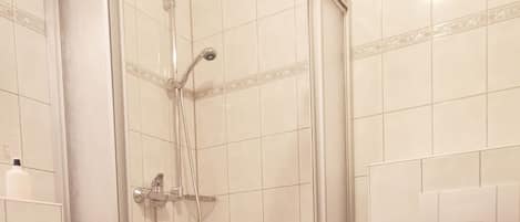 Un baño con ducha de vidrio, lavamanos e inodoro.
