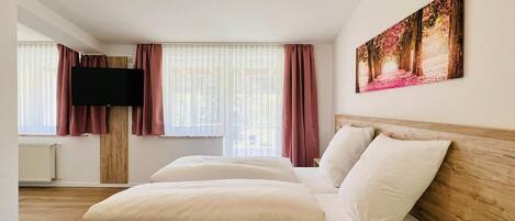 Una habitación de hotel con una cama grande, un televisor de pantalla plana montado en la pared y un cuadro sobre la cama.