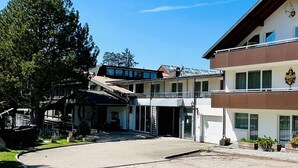 A two-story building with a balcony, large windows, and a logo on the facade. - Tanneneck (Löffingen)