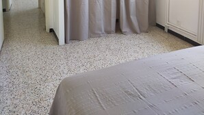 Une chambre à coucher avec un lit, une fenêtre avec des stores, une porte et un rideau.