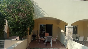 An outdoor patio area with a table and chairs, a stone wall, and a large tree providing shade. - 2 Bedroom House Sleeps 6 - Pool, Hot Tub, Garden (Mandria)