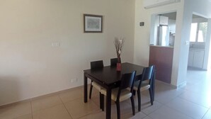 A dining area with a dark wooden table and chairs, a vase with branches, and a framed picture on the wall. - 2 Bedroom House Sleeps 6 - Pool, Hot Tub, Garden (Mandria)