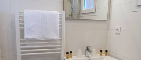 Un baño moderno con tocador blanco, perchero, espejo y zona de ducha.