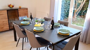 A dining table set with plates, glasses, and a bottle, surrounded by chairs.