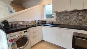 A modern kitchen with a washing machine, oven, and a window providing natural light.