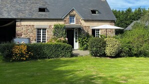 Una casa de piedra con techo inclinado, un garaje y un césped bien cuidado.