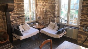 Una habitación acogedora con paredes de piedra, dos camas con ropa blanca, una mesita redonda y una silla.