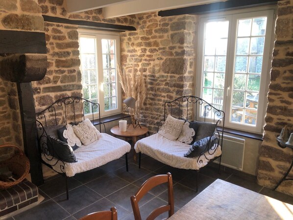 A cozy room with stone walls, two beds with white bedding, a small round table, and a chair. - Le Giré Cottage with a private spa, 10 minutes from the ocean, and a fenced-in lot of 200 m² (Hudimesnil)