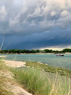 A boat on a calm river with a sandy beach and grassy areas in the foreground. - Le Giré Cottage with a private spa, 10 minutes from the ocean, and a fenced-in lot of 200 m² (Hudimesnil)