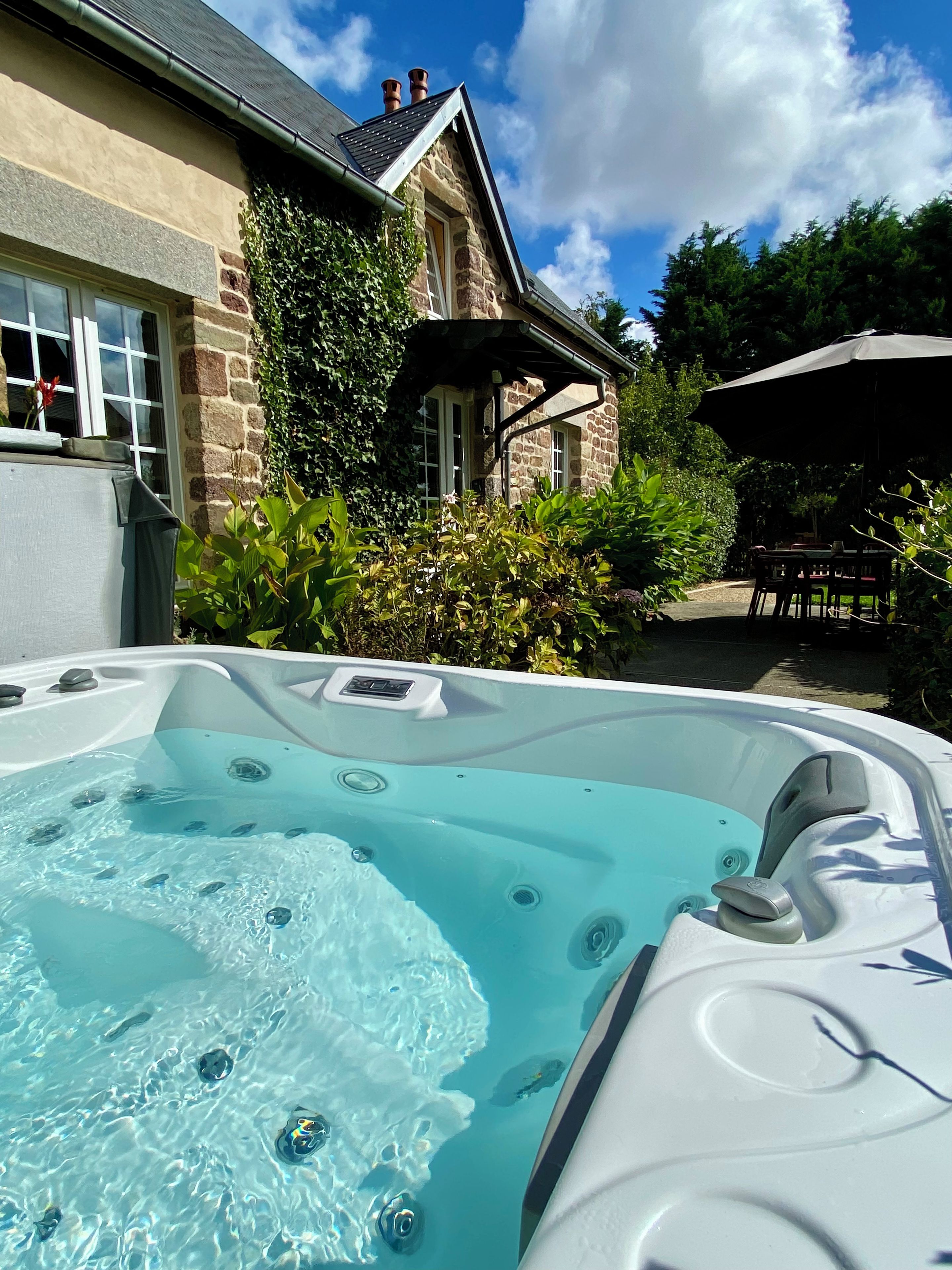 A hot tub with a stone house in the background.