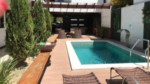 A pool area with lounge chairs, a wooden deck, and potted plants. - Pousada Buriti (Conceicao da Barra)