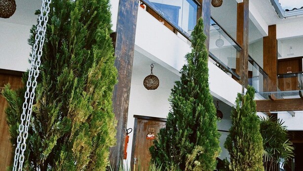 A modern building with a glass facade, wooden beams, and indoor plants. - Pousada Buriti (Conceicao da Barra)
