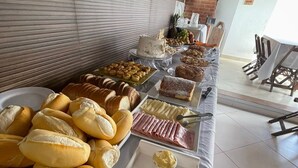 A buffet table with various food items including bread, pastries, and desserts. - Pousada Buriti (Conceicao da Barra)