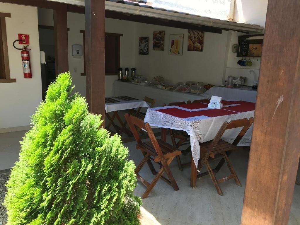 Een buiten eethoek met een tafel voor twee personen, omringd door houten stoelen. Een kleine potplant staat op de voorgrond.