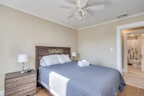 A bedroom with a bed, nightstand, lamp, and a ceiling fan.