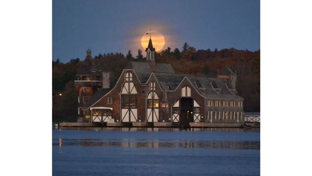 A waterfront building with a prominent tower and a large moon in the background. - Riverview Townhouse II in Downtown Alexandria Bay (Alexandria Bay)