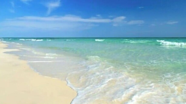 Ein Strand mit klarem, blauem Wasser und sandigem Ufer.