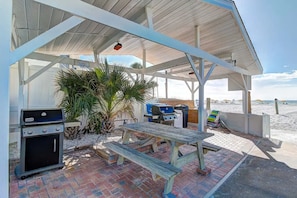 A covered outdoor area with a grill, a table, and a bench. - Beachfront Getaway in Siesta Key (Sarasota)