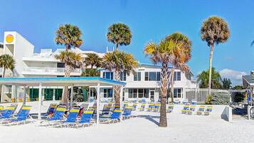 A beachside hotel with multiple lounge chairs and palm trees.
